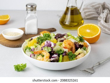 Grilled shrimp, lettuce, orange, red onion on a white background side view. Fresh seafood salad recipe.