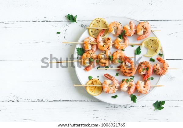 Grilled shrimp skewers. Seafood, shelfish.\
Shrimps Prawns skewers with spices and fresh herbs on white wooden\
background, copy space. Shrimps prawns brochette kebab. Barbecue\
srimps prawns.