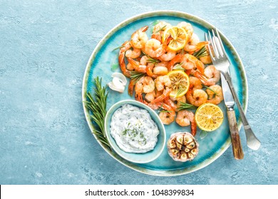 Grilled shrimps or prawns served with lemon, garlic and sauce. Seafood. Top view. 