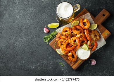 Grilled shrimps or prawns served with lime, garlic and white sauce on a dark concrete background. Seafood. Top view with copy space. Flat lay