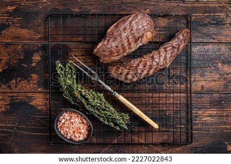 Grilled Sirloin flap or Bavette beef meat steak on a griil with herbs. Wooden background. Top view.