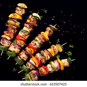 Grilled skewers of vegetables and meat  on the black background, top view