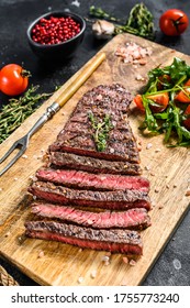 Grilled sliced Denver steak on a cutting board. BBQ beef. Black background. Top view - Shutterstock ID 1755773240