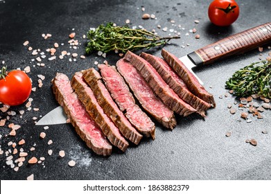 Grilled and sliced flat iron rare steak. Marble beef meat. Black background. Top view - Shutterstock ID 1863882379