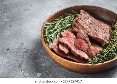 Grilled sliced Skirt Steak on a plate with herbs. Gray background. Top view. Copy space. - Shutterstock ID 2277627417