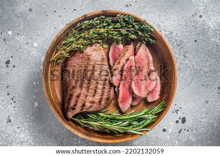 Grilled sliced Skirt Steak on a plate with herbs. Gray background. Top view.