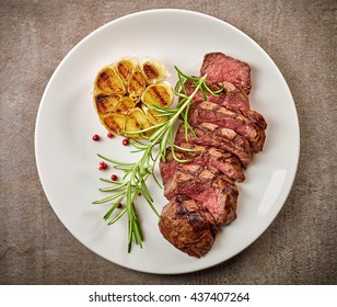 Grilled Sliced Steak And Rosemary On White Plate, Top View