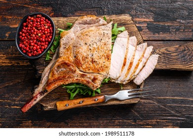 Grilled And Sliced Tomahawk Pork Chop Meat Steak On A Marble Board. Dark Wooden Background. Top View