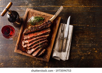 Grilled sliced Tomahawk Steak on bone and glass of Red wine on wooden background - Shutterstock ID 1973594753