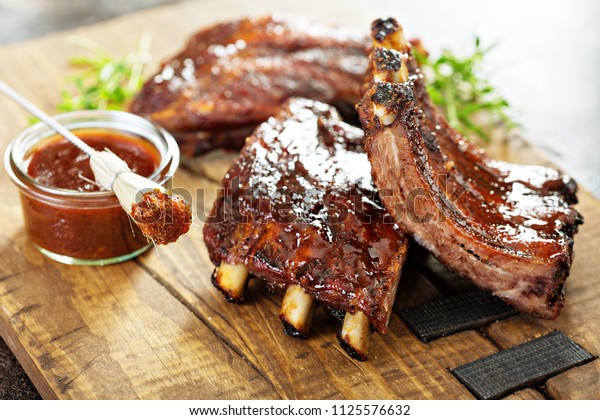 Grilled and smoked ribs with barbeque sauce on a\
carving board