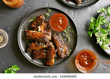 Grilled spare ribs on plate over black stone background. Tasty bbq meat. Top view, flat lay
