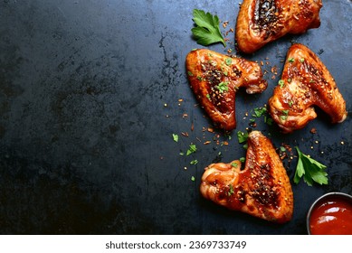 Grilled spicy chicken wings in mexican or chinese stile with ketchup on a black metal tray. Top view with copy space. - Shutterstock ID 2369733749