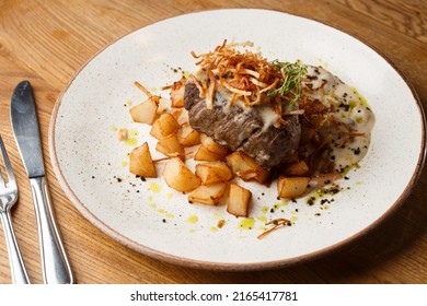 Grilled Steak With Baked Golden Potatoes Served With Crispy Onion On Top On A Brick Background. Delicious Recipe. Pork Fillet Cooked On Skillet For Dinner . Fried Juicy Meat Texture.