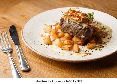 Grilled Steak With Baked Golden Potatoes Served With Crispy Onion On Top On A Brick Background. Delicious Recipe. Pork Fillet Cooked On Skillet For Dinner . Fried Juicy Meat Texture.