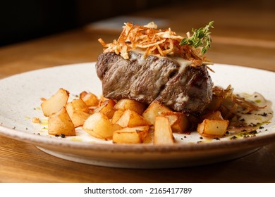 Grilled Steak With Baked Golden Potatoes Served With Crispy Onion On Top On A Brick Background. Delicious Recipe. Pork Fillet Cooked On Skillet For Dinner . Fried Juicy Meat Texture.