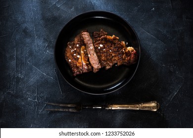 Grilled Steak Ribeye Well Done On A Plate And Meat Fork, Top View