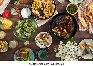 Grilled Steak, Grilled Vegetables, Potatoes, Salad, Different Snacks And Homemade Lemonade On Rustic Wooden Table, Overhead View