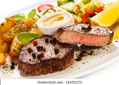 Grilled steaks, baked potatoes and vegetable salad