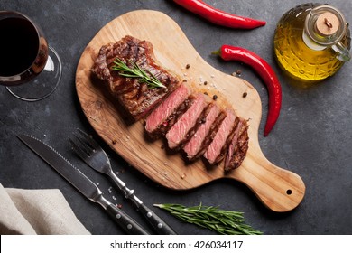 Grilled Striploin Sliced Steak And Red Wine Over Stone Table. Top View