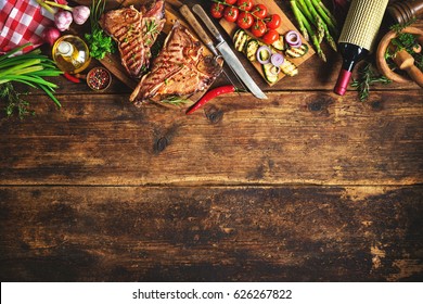 Grilled T-bone beef steaks with fresh herbs, vegetables and wine bottle on rustic wooden board - Powered by Shutterstock