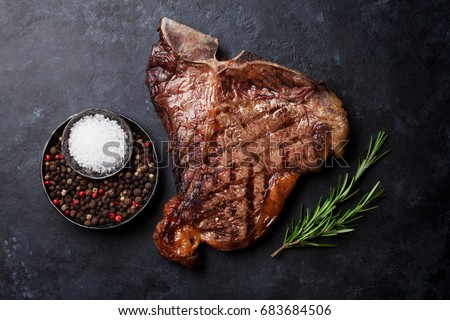 Grilled T-bone steak on stone table. Top view