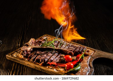 Grilled  T-bone   Steak And Vegetables  With Fire On Dark Wood Table.