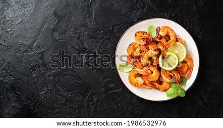 Grilled tiger shrimps with spice and lime. Black background. Top view, space for text.