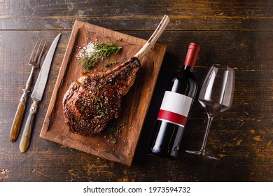 Grilled Tomahawk Steak on bone and bottle of Red wine on wooden background