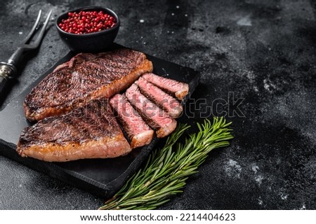 Grilled top sirloin or cup rump beef meat steak on marble board. Black background. Top view. Copy space.