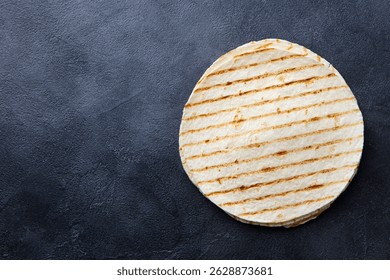 Tortilla a la parrilla, lavash, pan plano sobre fondo gris oscuro. Copiar espacio. Vista superior.