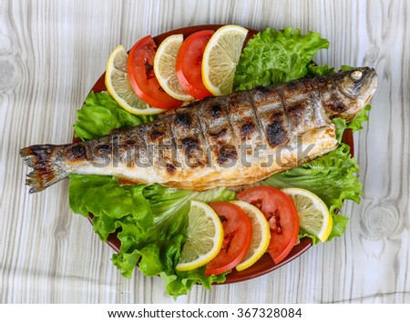 Grilled trout barbeque served lemon, tomato and salad leaves