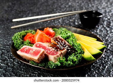 Grilled Tuna Steak And Avocado On A Black Plate