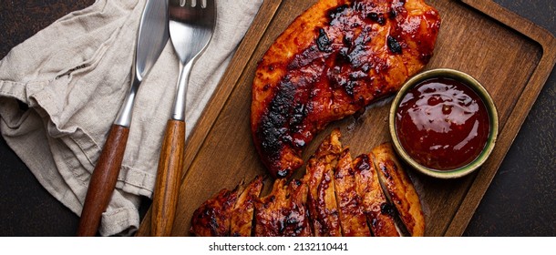 Grilled Turkey Or Chicken Marinated Fillet With Red Sauce Served And Sliced On Wooden Cutting Board On Stone Brown Background From Above, Poultry Breast Barbecue 