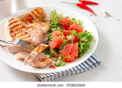 Grilled Turkey Steaks And Lettuce Salad With Grapefruit In A Plate On A White Concrete Table Close-up. Healthy Diet Food. Tasty Lunch With Turkey Meat.