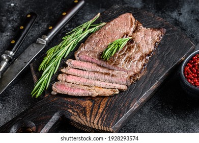 Grilled Veal Meat Chop Steak On A Cutting Board. Black Background. Top View.