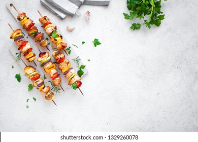 Grilled vegetable and chicken skewers with  bell peppers, zucchini, onion and mushrooms on white background, top view, copy space. Meat and vegetables kebabs on skewers.