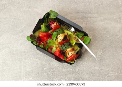 Grilled vegetable and chicken skewers with bell peppers, zucchini, tomatoes and lettuce in take-away container on gray background, top view, restaurant dish. Meat and vegetables kebabs on skewers.