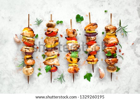 Grilled vegetable and chicken skewers with  bell peppers, zucchini, onion and mushrooms on white marble background, top view. Meat and vegetables kebabs on skewers.
