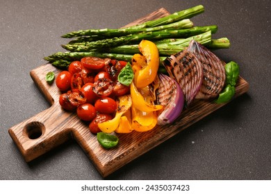 Grilled vegetables: asparagus,tomatos,onion on a wooden board on a black background - Powered by Shutterstock