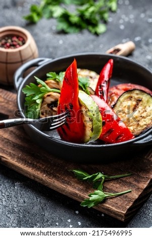 Grilled vegetables colorful bell pepper, zucchini, eggplant with herbs in a cast iron grilling pan over stone, concrete background. vertical image. top view. place for text,