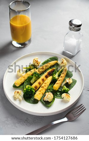 grilled vegetables and juice on a light stone background, dietary vegetarian snack babycorn, healthy low-calorie food, vertical frame empty space