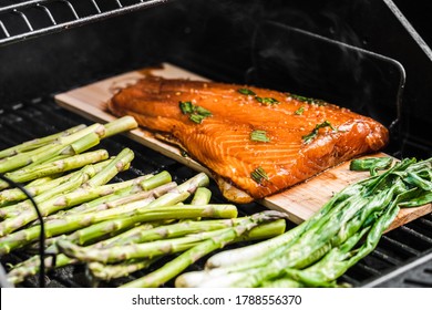 Grilled Veggies On A Charcoal Grill. Asparagus And Onions Caramelizing. Salmon On A Cedar Wood Plank Grilling And Smoking. 