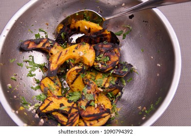 Grilled Winter Squash Salad In A Stainless Steel Bowl With Serving Spoon.