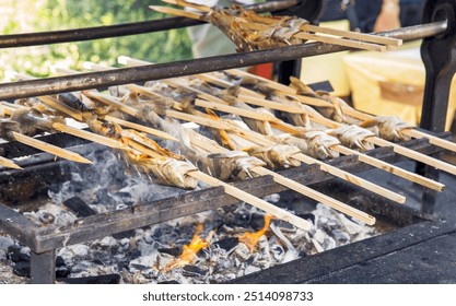 Grilling fish on skewers over open fire, traditional Japanese outdoor cooking, charcoal grilling concept - Powered by Shutterstock