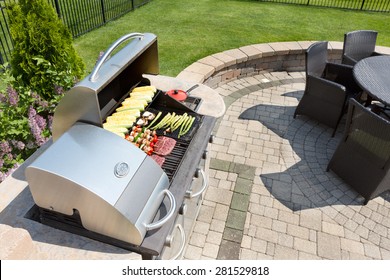 Grilling healthy food with corn, kebabs, meat and sausages on an outdoor gas barbecue on a luxury brick paved patio and summer kitchen in a neatly manicured back yard