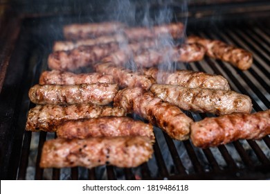Grilling Meat on barbecue grill with hot coal. Preparing, cooking cevapcici, kebabs, country sausage on charcoal barbecue BBQ in outside fireplace. Traditional Turkish, Bosnian, Serbian, Croatian food