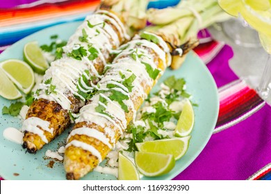 Grilling mexican street corn elote garnished with spices and fresh cilantro on a serving plate.