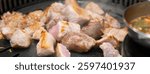 Grilling pork meat on a iron BBQ board in Korean restaurant, fresh delicious food cuisine lifestyle.