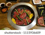 Grilling raw thin sliced beef on the hot charcoal stove, Japanese barbecue style also know as Yakiniku.
