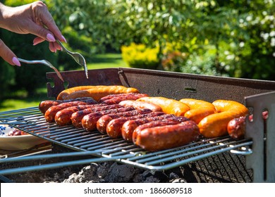 Grilling sausages in the open air. The concept of barbecue, spending time together. Hanging out in the garden with family and friends. - Powered by Shutterstock